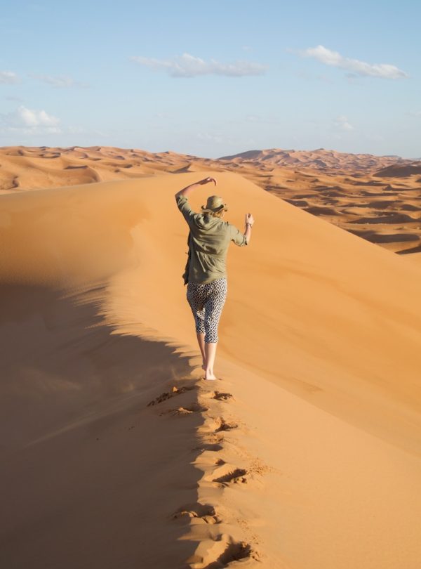 A man walking across a sandy dune in the desert