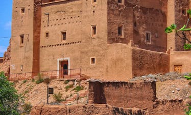 A stunning view of a traditional Kasbah in Kelâat M'Gouna, Morocco under a clear blue sky.