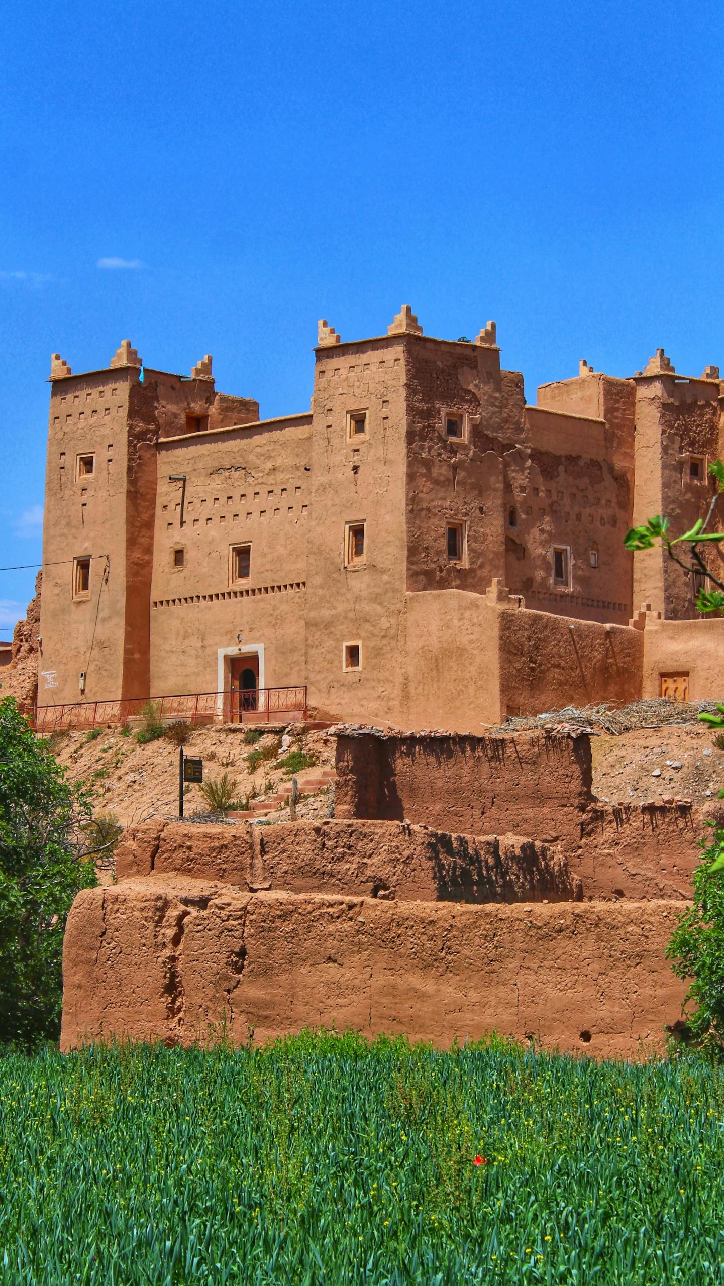 A stunning view of a traditional Kasbah in Kelâat M'Gouna, Morocco under a clear blue sky.